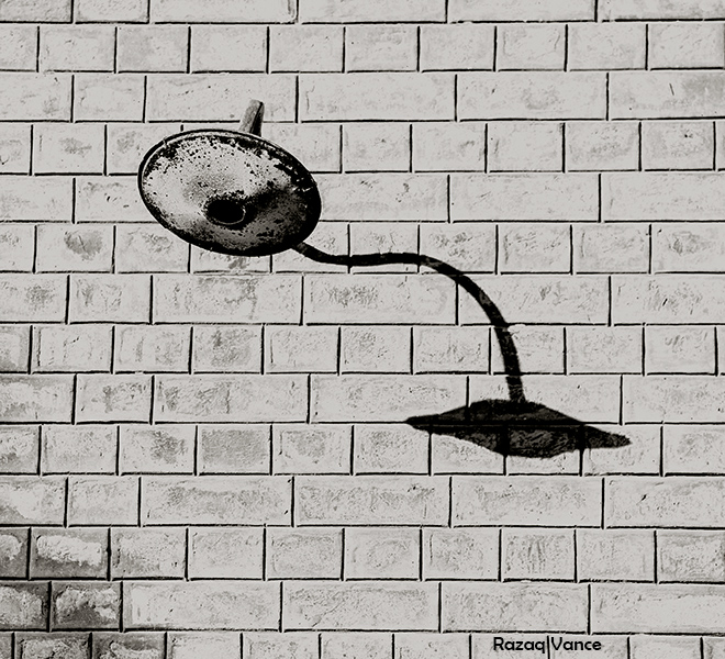 Long Shadow of Abandoned Bulb Holder on a Brick Wall